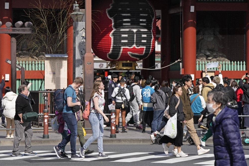 Tourists in Tokyo's Asakusa district ditch their jackets amid unseasonably warm temperatures in the capital and across Japan on Thursday. 