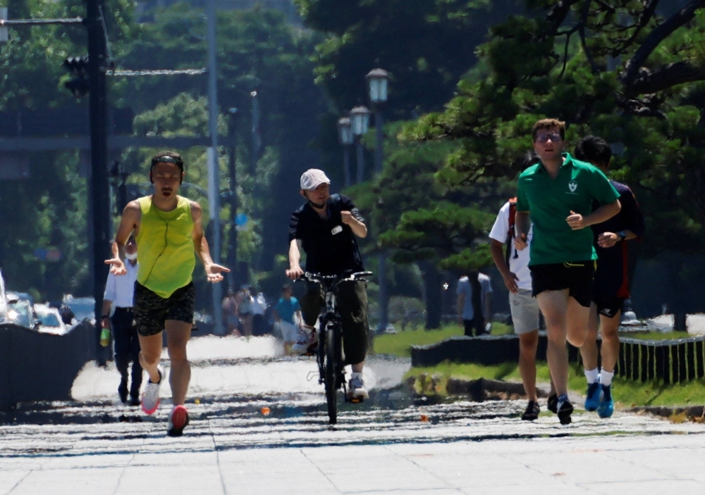 Joggers near the Imperial Palace in Tokyo. Over just one week of a scorching summer the Yomiuri Shimbun daily reported that 935 people were hospitalized for heatstroke and over 500 schools were shut down from Aug. 21 to 27.