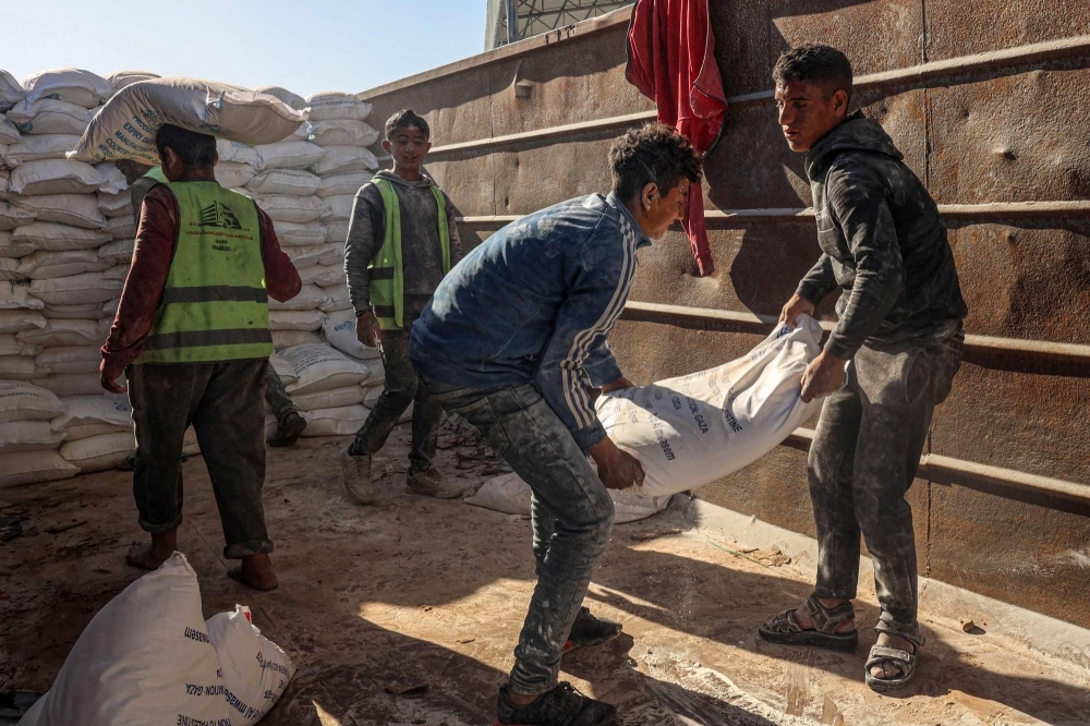 Workers unload bags of humanitarian aid that entered Gaza by truck in Rafah in the southern Gaza Strip on Saturday.