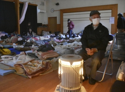 An evacuee keeps himself warm around a heater at an evacuation center in Wajima, Ishikawa Prefecture, in January.