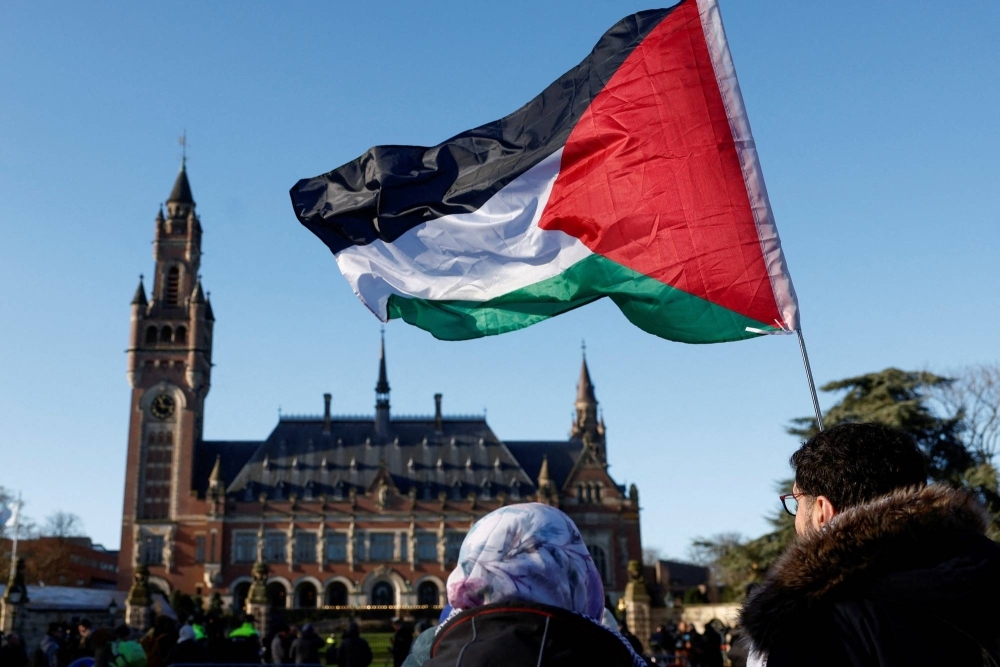 Protesters hold a Palestinian flag as they gather outside the International Court of Justice as judges rule on emergency measures against Israel following accusations by South Africa that the Israeli military operation in Gaza is a state-led genocide, in The Hague on Jan 24.
