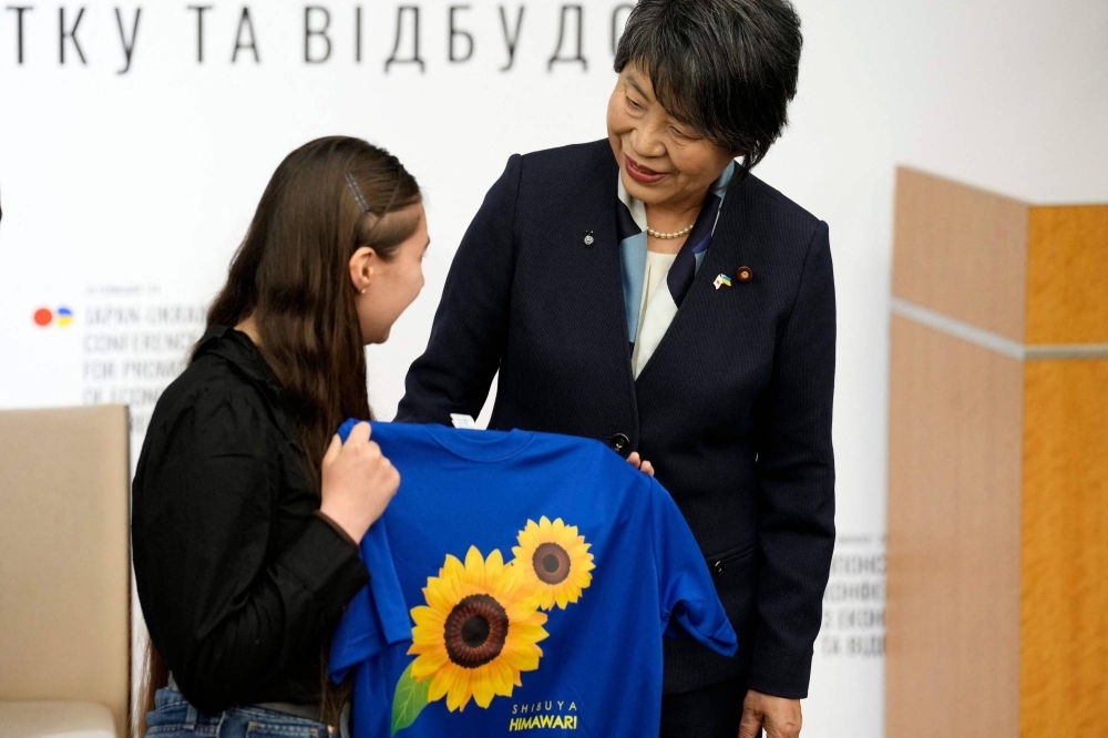 Foreign Minister Yoko Kamikawa (right) presents a gift to a Ukrainian refugee an event at the Keidanren Kaikan in Tokyo on Monday.