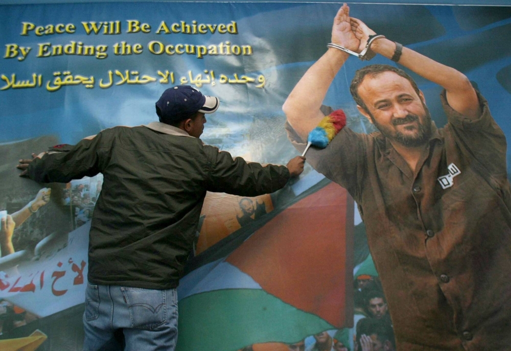 A supporter of jailed Fatah leader Marwan Barghouti in the West Bank city of Ramallah in front of a poster depicting Barghouti.