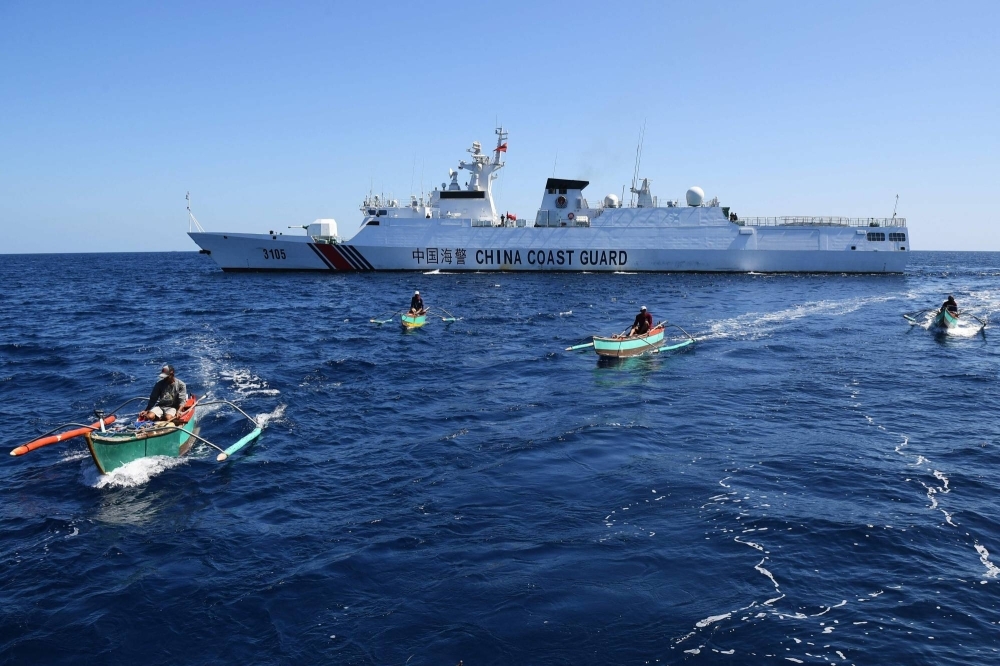 Filipino fishermen aboard their wooden boats sail past a Chinese coast guard ship near the China-controlled Scarborough Shoal, in disputed waters of the South China Sea on Feb. 15. 