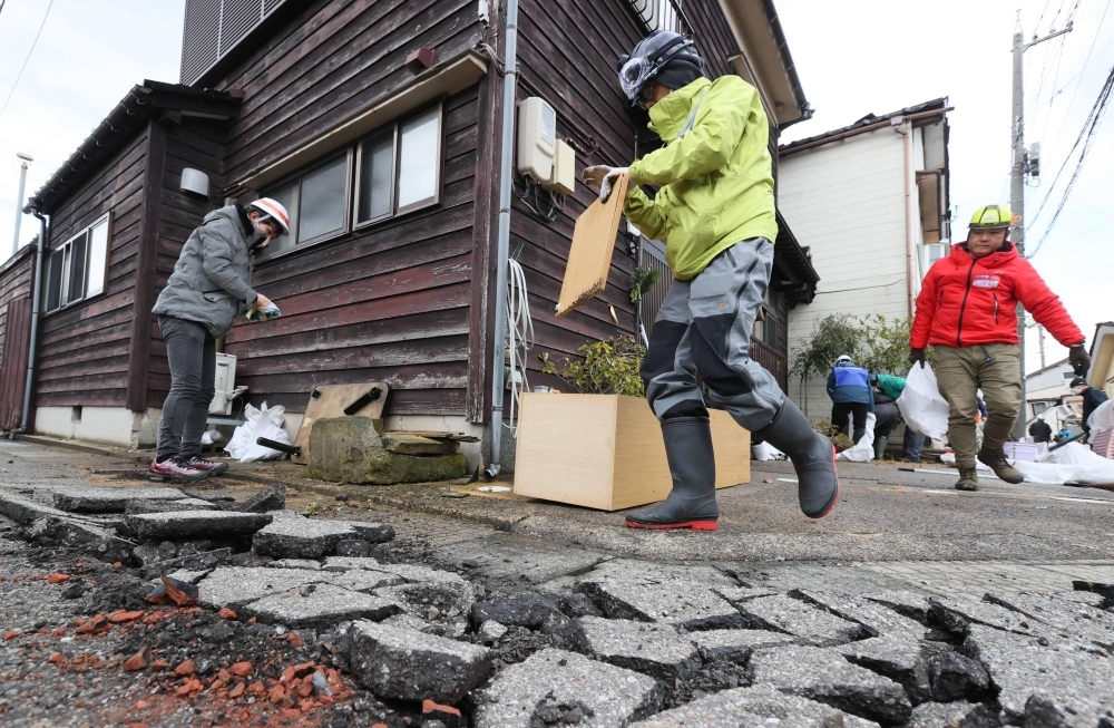 Volunteers carry disaster waste out of houses damaged by the New Year's Day quake, in Wajima, Ishikawa Prefecture, on Feb. 10.