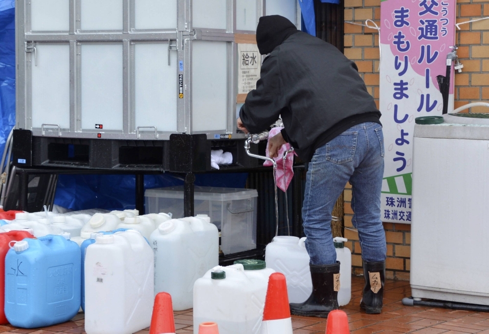 A man pours water into a plastic tank at an evacuation shelter in the city of Suzu, Ishikawa Prefecture, on Feb. 1.