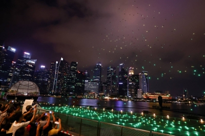 People take pictures of the city skyline lit up by drones during a performance to welcome the Lunar New Year of the Dragon, at Marina Bay in Singapore on Feb. 10.