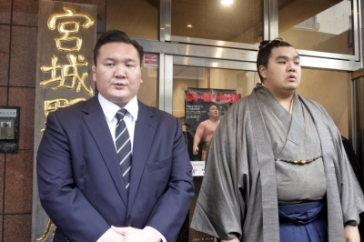 Former yokozuna Hakuho apologizes for the bullying caused by his protege Hokuseiho (right), outside the Miyagino stable in Tokyo on Friday. 