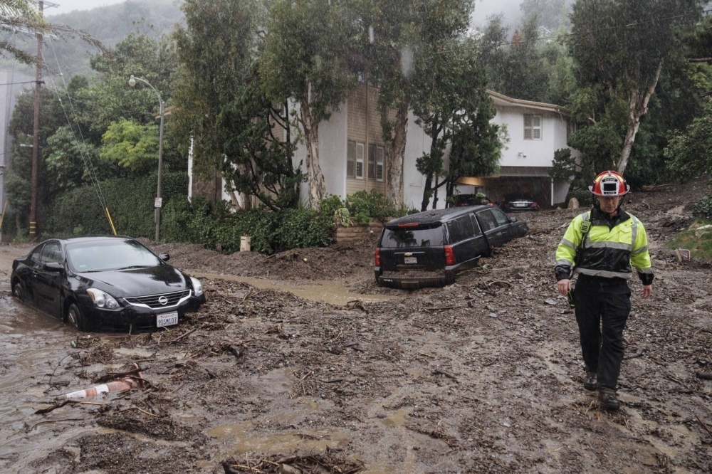 A firefighter walks on mud and rocks from a mudslide during a storm in Los Angeles on Feb. 5.