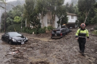 A firefighter walks on mud and rocks from a mudslide during a storm in Los Angeles on Feb. 5. | Bloomberg