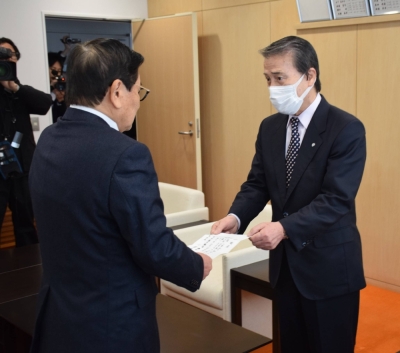 Hideo Kojima (right), mayor of Ginan, Gifu Prefecture, hands his letter of resignation to the head of the town's assembly at the town hall on Thursday.