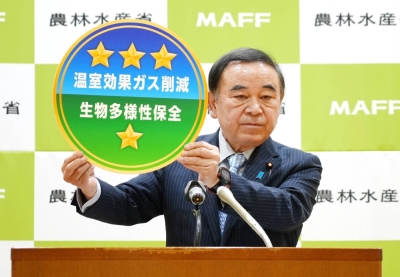 Agriculture minister Tetsushi Sakamoto shows a mock-up of a label for vegetables grown in a sustainable way at his ministry on Friday.