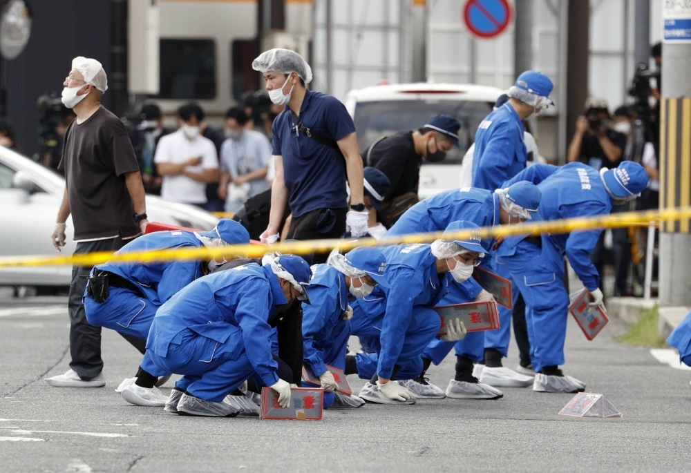 Investigators at the site of the murder of former Prime Minister Shinzo Abe with a handmade gun in the city of Nara in July 2022