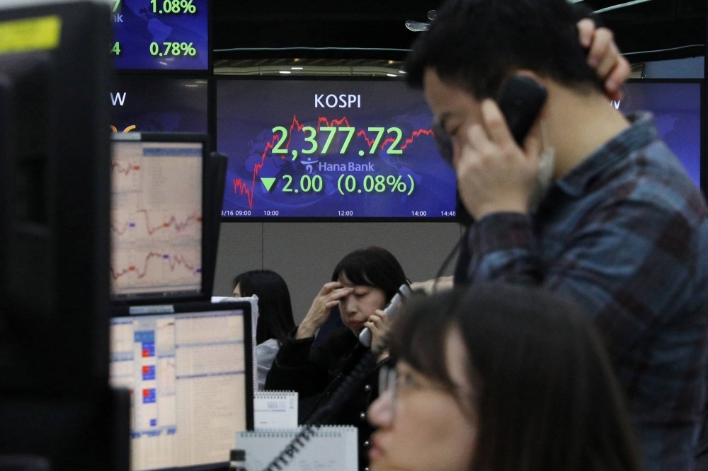 Currency dealers work in front of an electronic board showing the Korean Composite Stock Price Index (KOSPI) at a dealing room of a bank in Seoul. Officials in South Korea are taking a cue from Japan, where a push for corporate reforms has been one of the key drivers for a world-beating equity rally.