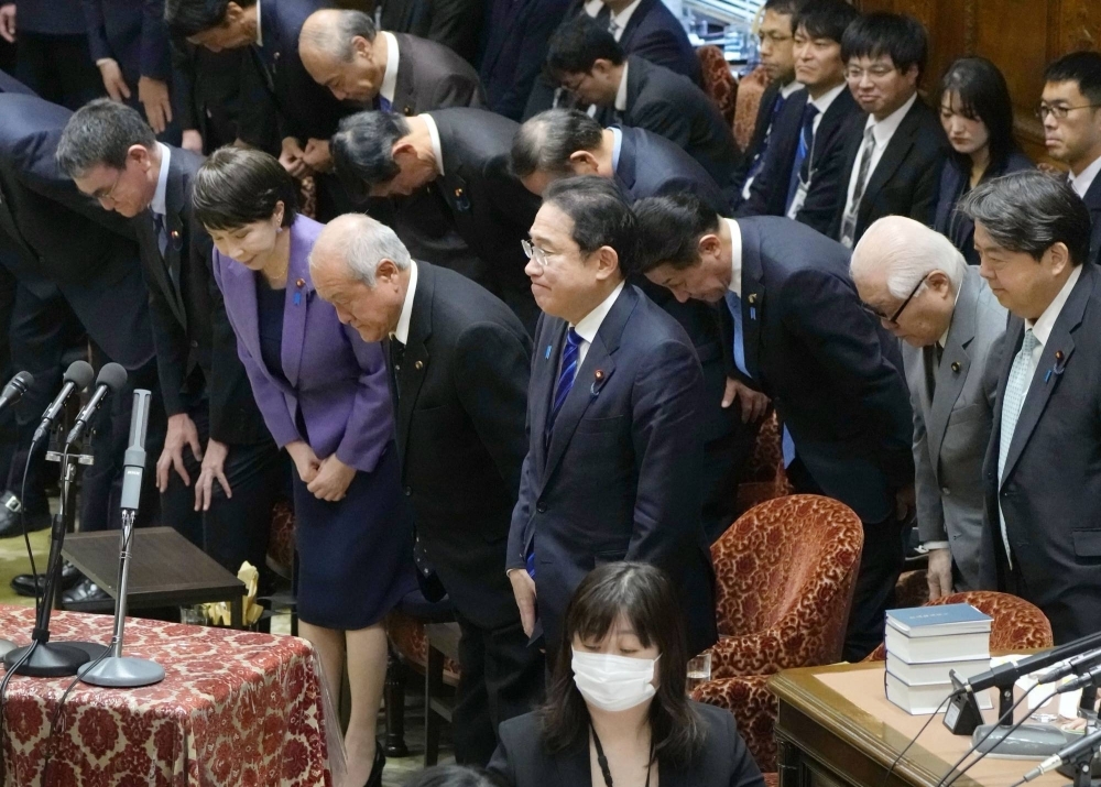 Prime Minister Fumio Kishida and other lawmakers bow after the Lower House passed the fiscal 2024 draft budget on Saturday. 
