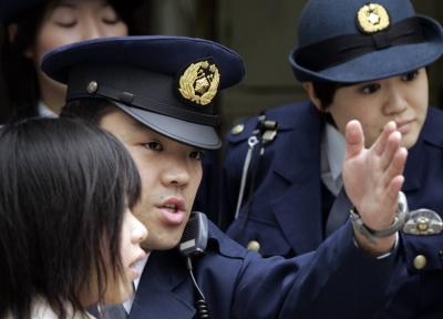 Police officers assist a woman in front of a police box in Tokyo.