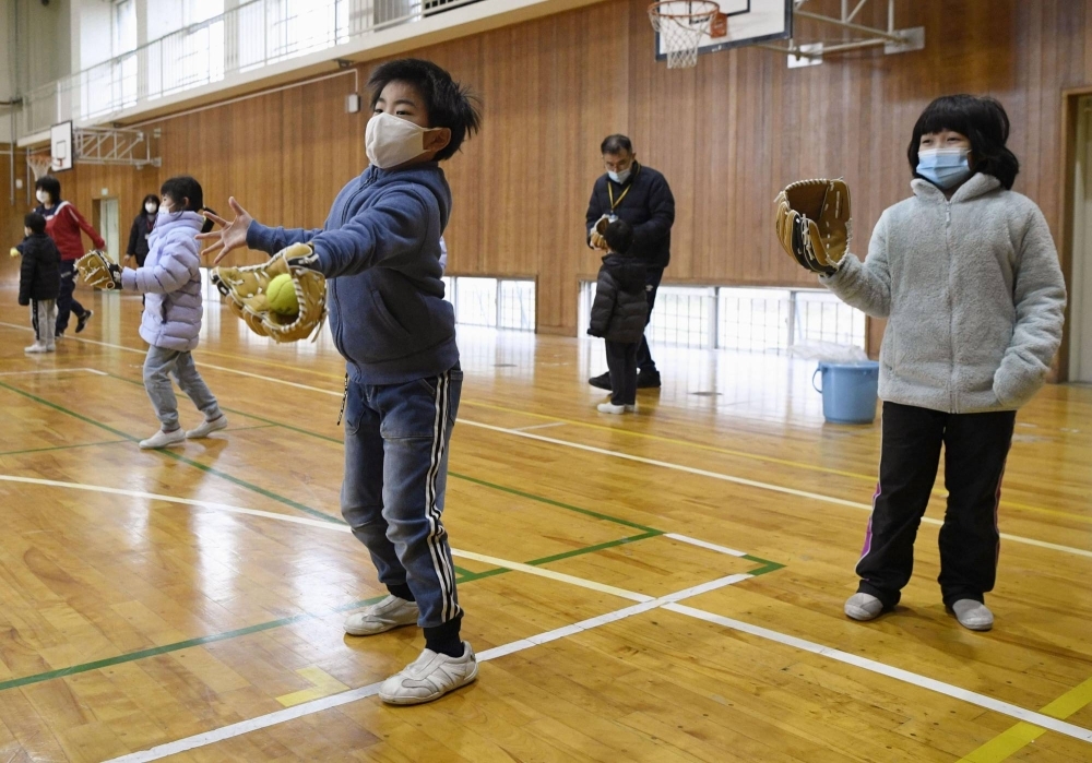 Students play catch using baseball gloves donated by Ohtani at Monzen East Elementary School on Monday.