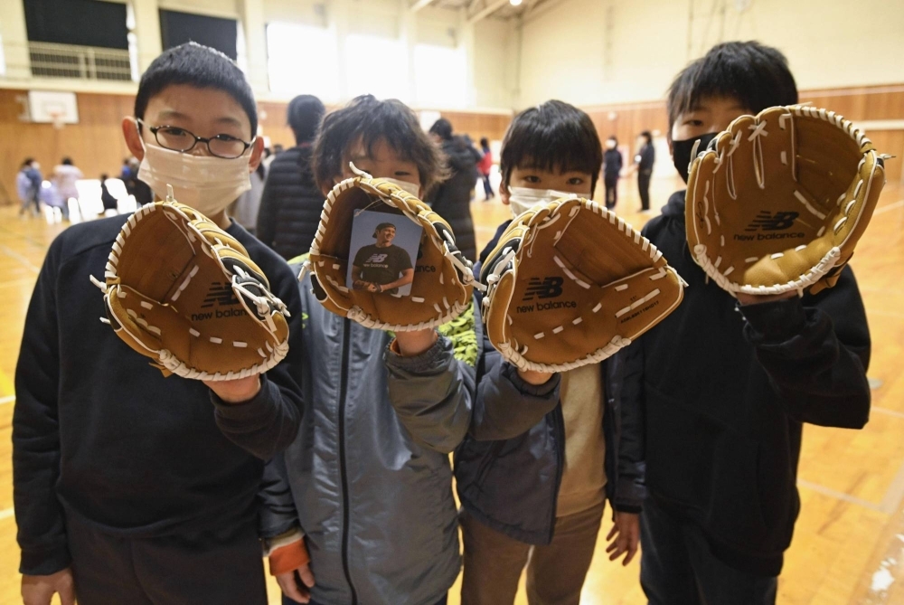Elementary school pupils hold baseball gloves donated by Los Angeles Dodgers star Shohei Ohtani at Monzen East Elementary School in Wajima, Ishikawa Prefecture, on Monday.