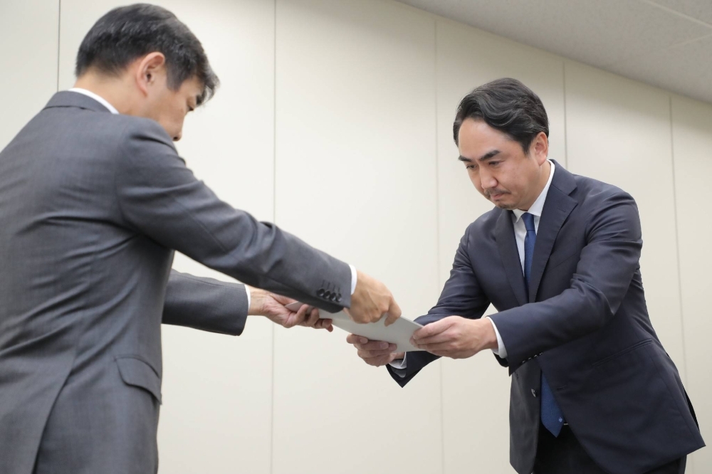 Takeshi Idezawa, president of LY (right), receives administrative guidance from a communications ministry official at the ministry on Tuesday.
