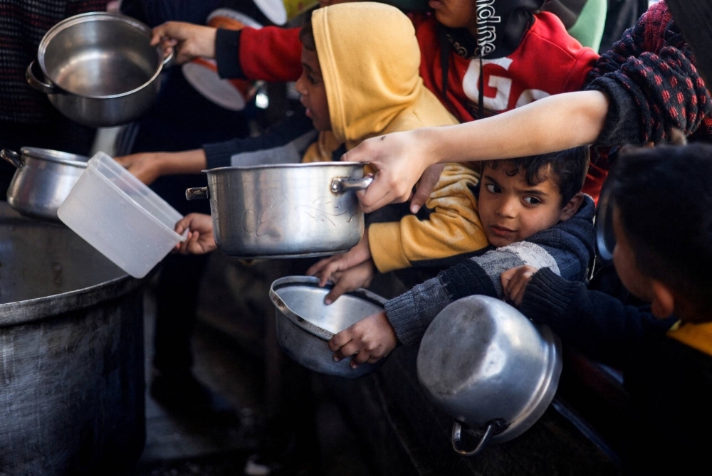 Palestinian children wait to receive food cooked by a charity kitchen amid shortages of supplies in Rafah, in the southern Gaza Strip, on Tuesday.