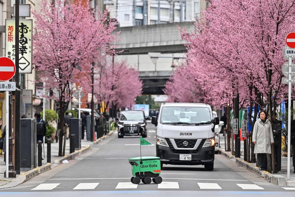 An unmanned robot navigates across a street during a demonstration of Uber Eats' robot delivery service in Tokyo on Tuesday.