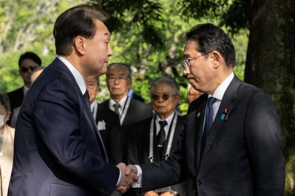 South Korean President Yoon Suk-yeol and Prime Minister Fumio Kishida shake hands in Hiroshima on May 21. The two leaders have met seven times in a year.