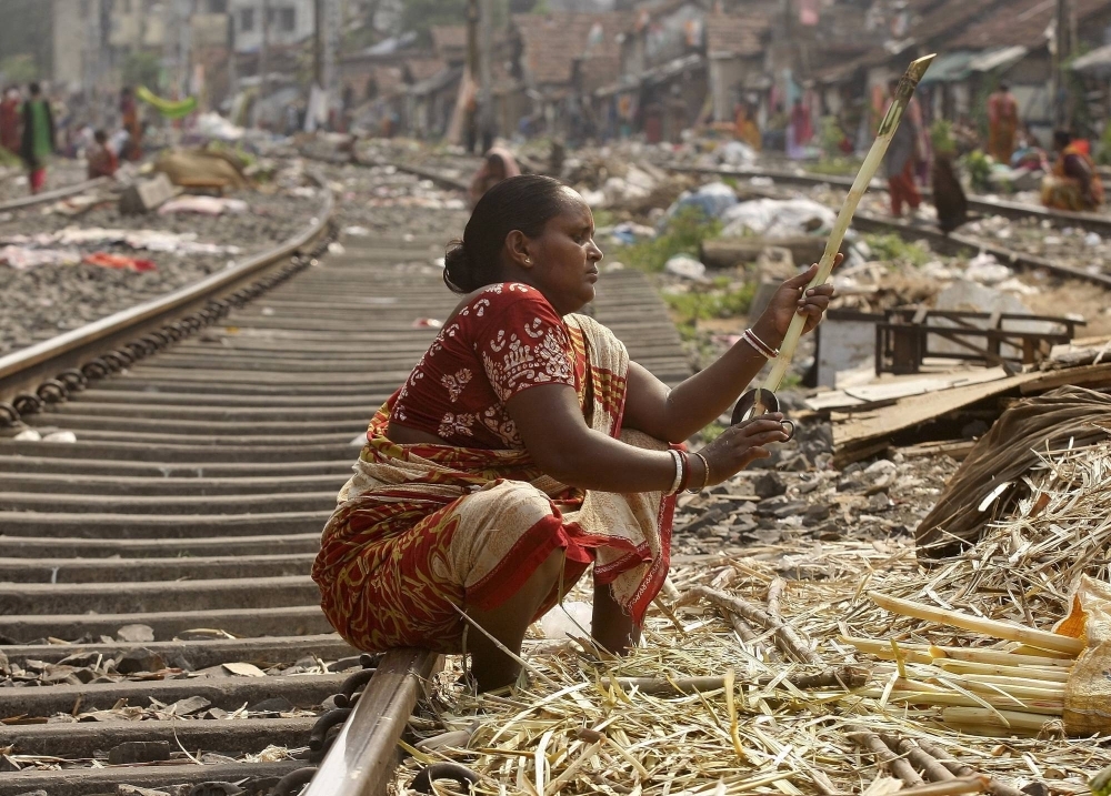 A woman peels sugar cane on a railway track to sell it to sugar cane juice vendors in a slum area in Kolkata.