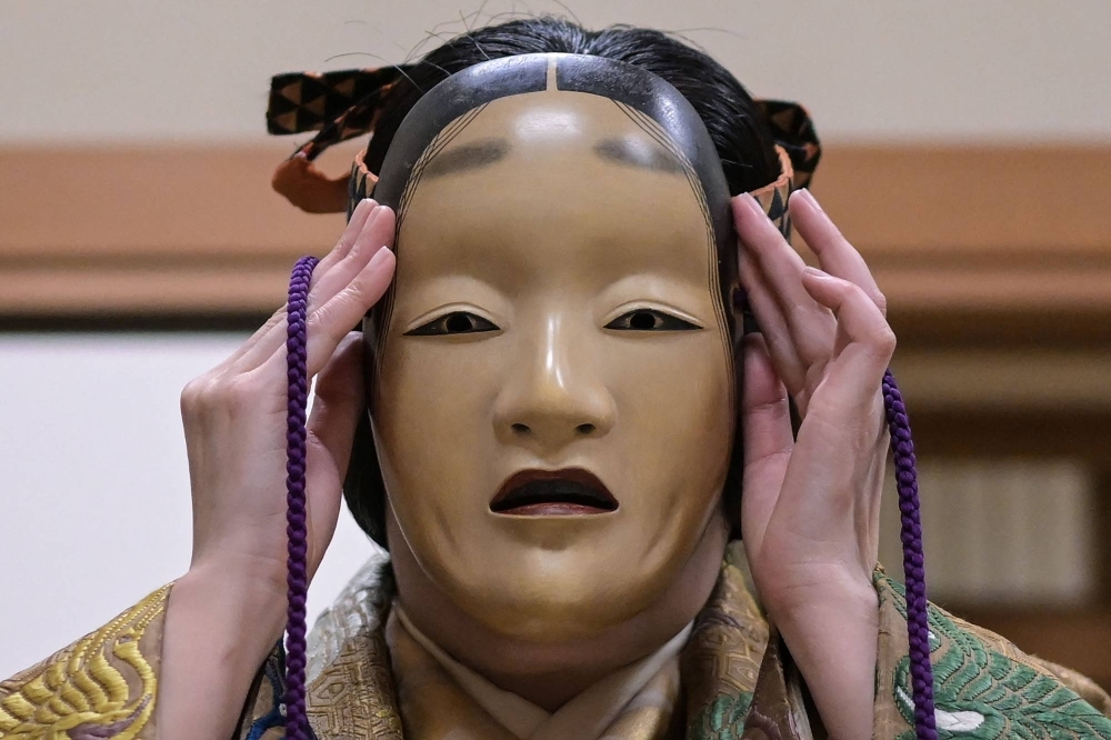 Mayuko Kashiwazaki tries on her mask after getting into costume before a dress rehearsal for "Dojoji," a famous noh drama about the revenge of a betrayed woman. 
