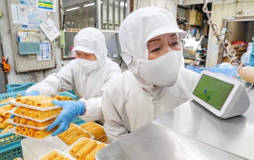 A worker at Nakamatsu Meat speaks to an Alexa-powered device at its factory in Uruma, Okinawa Prefecture, in November. At the factory, workers give production updates to Alexa, which then converts this into data that is compiled in the company's computer.