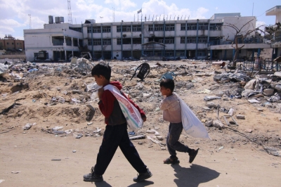 Palestinian children carrying sacks walk past the rubble of a building amid the Israeli offensive in Khan Younis, in the Gaza Strip, on Friday.