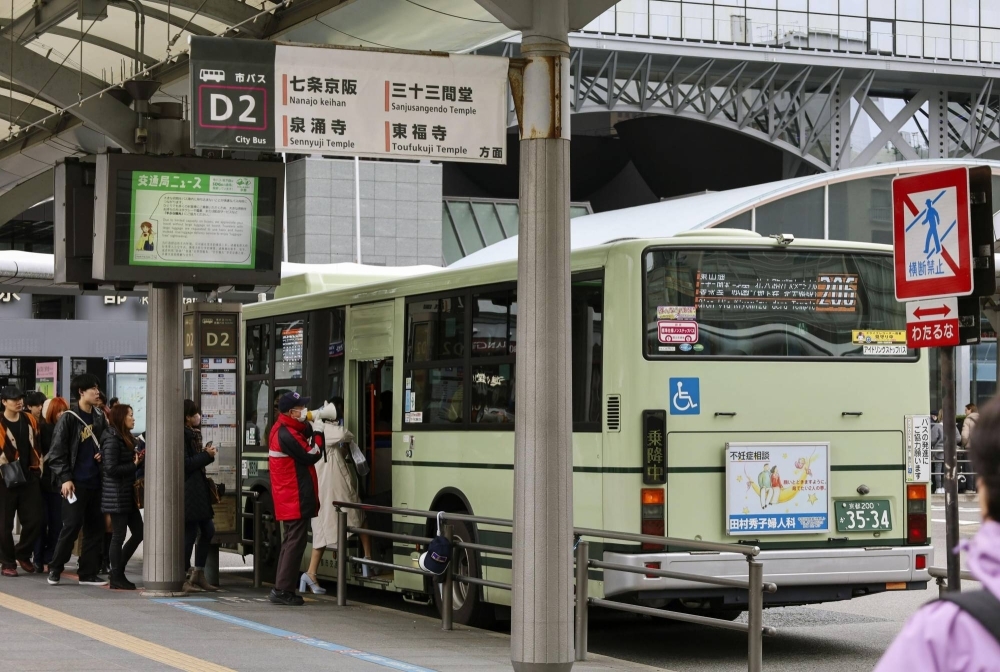 People line up to board a city bus outside JR Kyoto Station in Kyoto on Feb. 29.