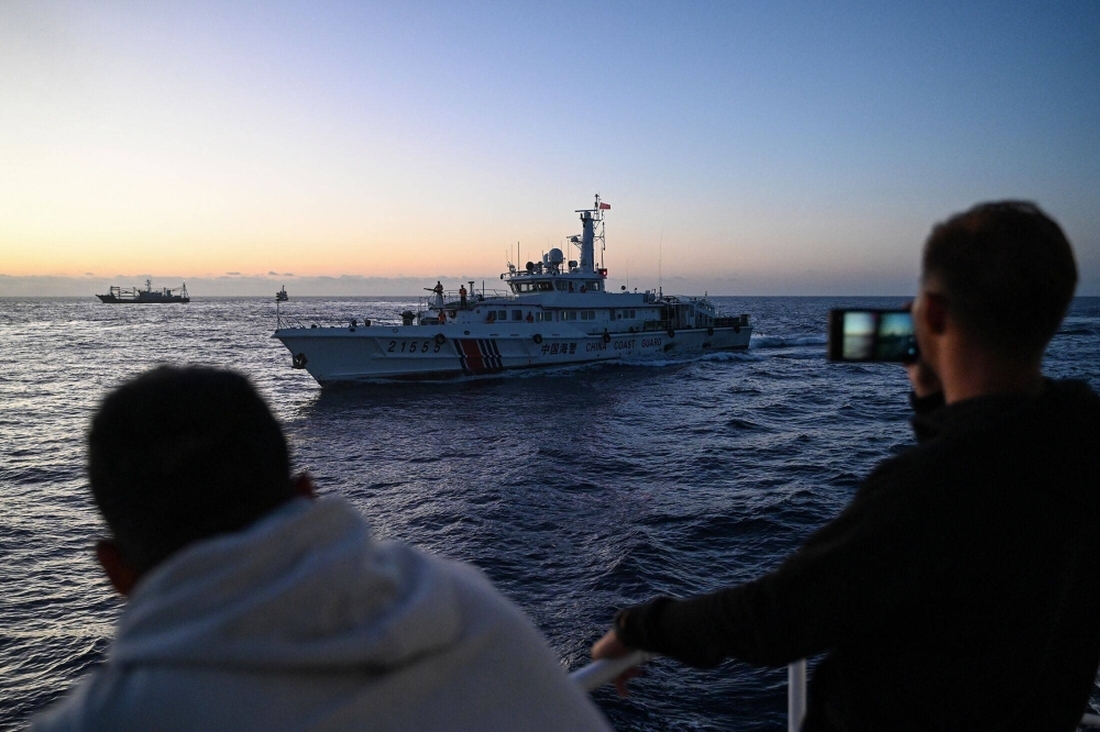 Philippine Coast Guard personnel film a China Coast Guard vessel during a supply mission in the disputed South China Sea on March 5.