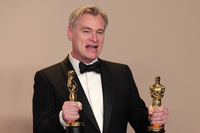 Christopher Nolan poses with the Oscars for best picture and best director for "Oppenheimer," in the Academy Awards press room on Sunday. 