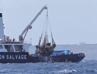 The wreckage of a Ground Self-Defense Force helicopter is salvaged by a vessel off Ikema Island in Okinawa Prefecture last May. | JIJI 

