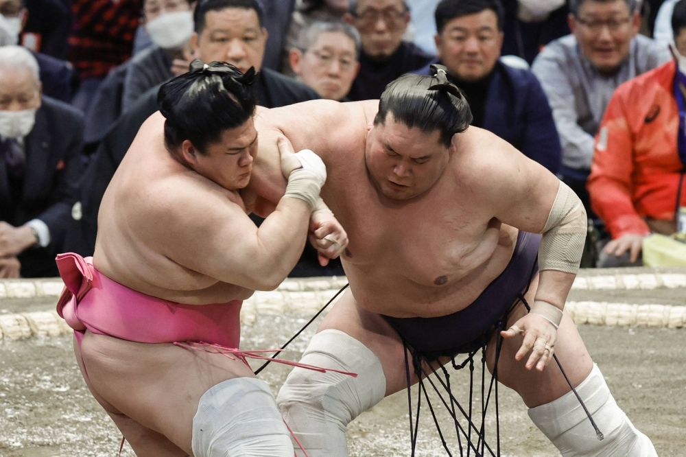 Terunofuji (right) defeats Ura on the second day of the Spring Grand Sumo Tournament at Edion Arena Osaka on Monday.