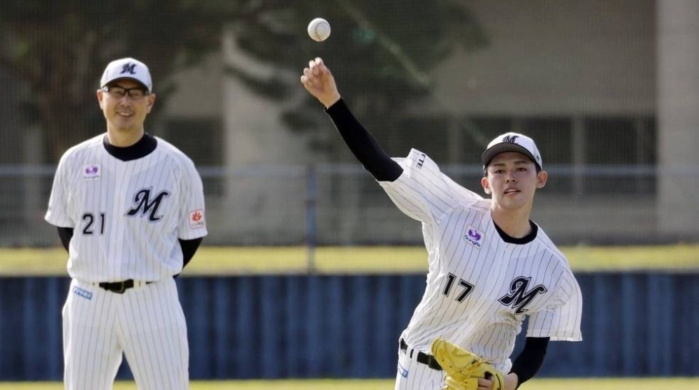 Lotte Marines manager Masato Yoshii (left) watches as ace pitcher Roki Sasaki throws in spring training in Ishigaki, Okinawa, in February 2023.
