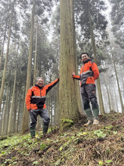 Shintaro Tajima (left) and his son, Daisuke, pose in their forest in Hita, Oita Prefecture, in January. At their feet is wasabi growing in clusters.