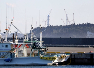 Towers at the Fukshima No. 1 nuclear power plant visible beyond a port on Sunday