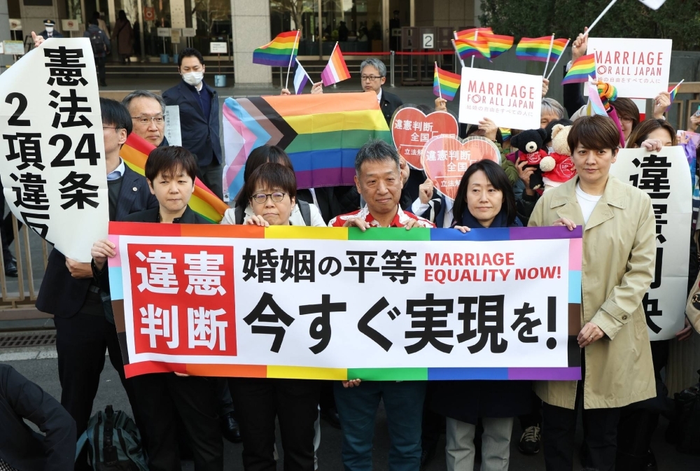 Plaintiffs of a lawsuit challenging the constitutionality of a ban on same-sex marriage and their supporters hold a banner calling for authorities to allow such unions in front of the Tokyo District Court on Thursday.