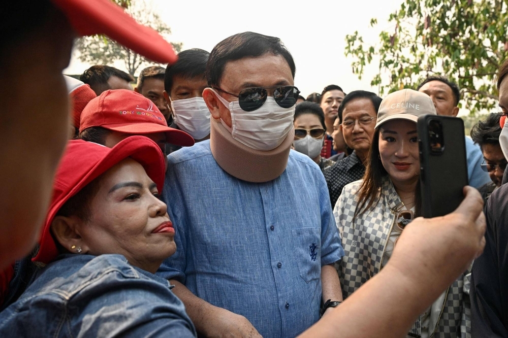 Former Thai Prime Minister Thaksin Shinawatra takes a photo with a supporter alongside his daughter, Paetongtarn Shinawatra (right), in Chiang Mai on Thursday.