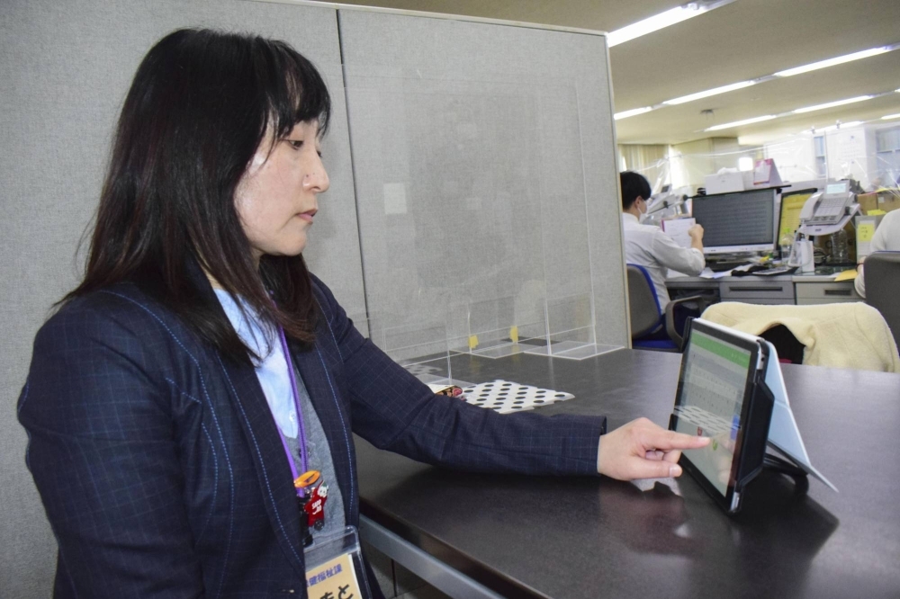 A Sapporo municipal official uses a telephone relay service at the city office in April last year.