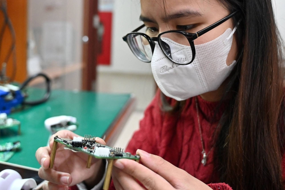 A student at Hanoi University of Science and Technology looking at a printed circuit board in the school's lab in Hanoi.