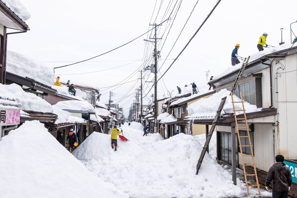 Residents remove snow from rooftops together with workers from a snow removal company in Joetsu, Niigata Prefecture, in January 2021. In fiscal 2022, 49 people in Japan died during activities related to the clearing of snow. Of these, 39 people — or roughly 80% — were age 65 or older.