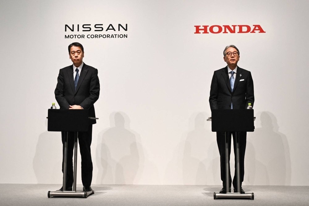 Makoto Uchida (left), president and CEO of Nissan, and Honda President Toshihiro Mibe give a joint news conference in Tokyo on Friday to announce a new strategic partnership in electric vehicles.