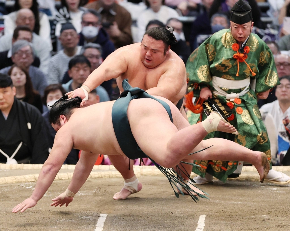 Takakeisho (back) pulls down Nishikigi on Saturday at the Spring Grand Sumo Tournament. 