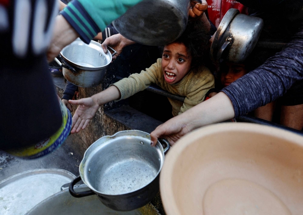 A Palestinian child waits to receive food cooked by a charity kitchen in Rafah, in the southern Gaza Strip. The United Nation's children's agency said on Sunday that many children in Gaza are suffering from severe malnutrition.