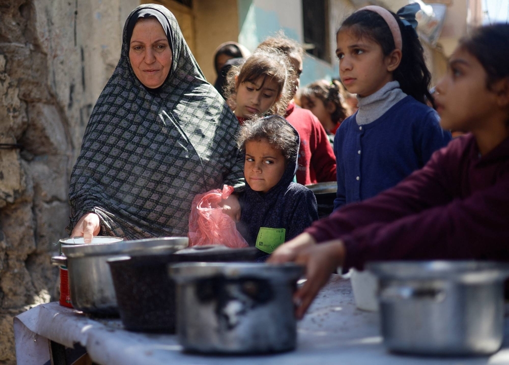 Palestinian children wait to receive food cooked by a charity kitchen amid shortages of food supplies, as the ongoing conflict between Israel and the Palestinian Islamist group Hamas continues, in Rafah, in the southern Gaza Strip, on March 5.