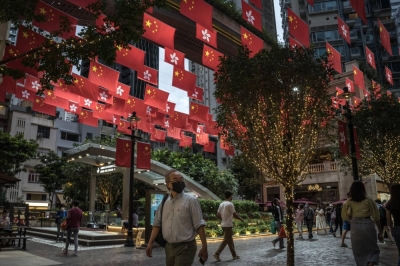 People walk under flags of China and the Hong Kong Special Administrative Region, on Queen's Road in Hong Kong.