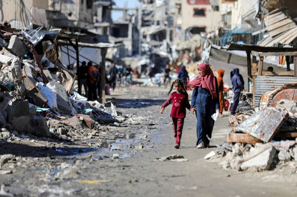Palestinians walk past the ruins of houses destroyed during Israel's military offensive in Gaza City on March 20.