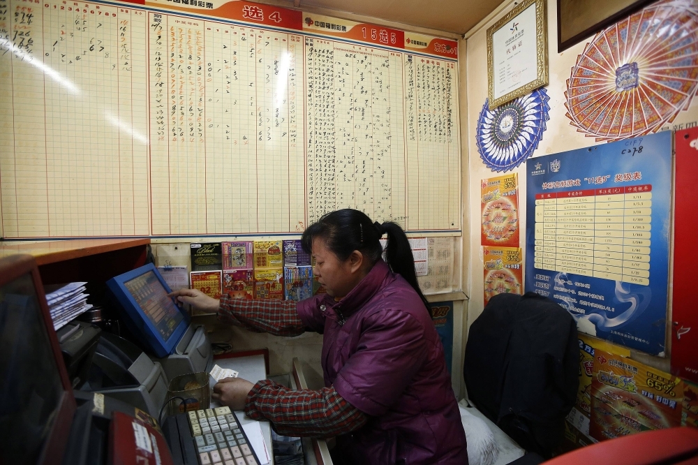 A woman checks a lottery ticket at a lottery ticket store in Shanghai